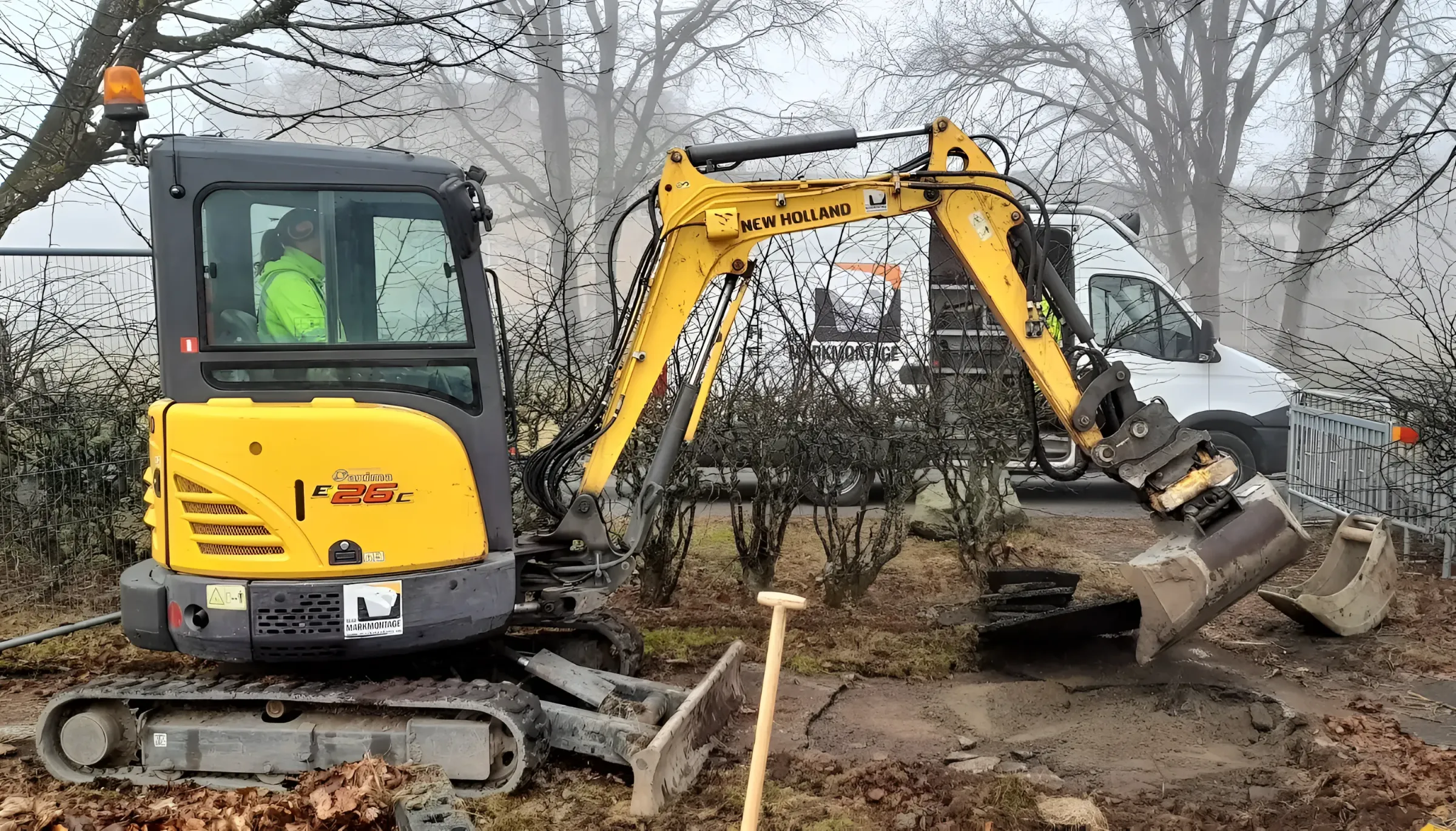 Gul minigrävare vid markarbete i en trädgård