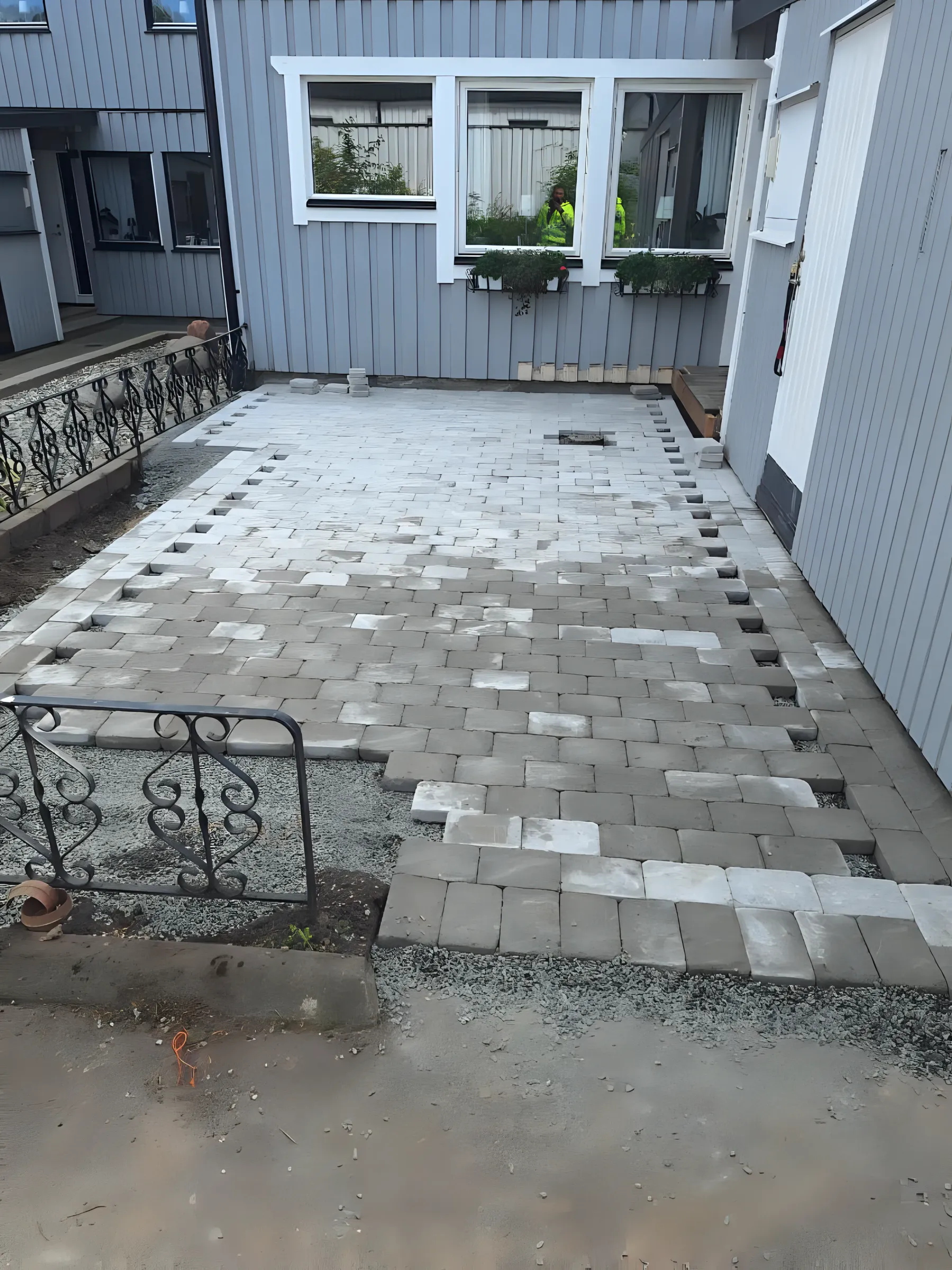 Marksten läggs på en gårdsplan framför ett hus